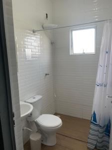 a white bathroom with a toilet and a sink at Apê Bianck's in Ilha Comprida