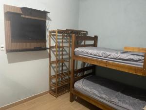 a room with two bunk beds and a flat screen tv at Apê Bianck's in Ilha Comprida