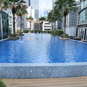 a large swimming pool with palm trees in a city at Vortex suites klcc by kl cozy home in Kuala Lumpur