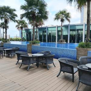a patio with tables and chairs next to a swimming pool at Vortex suites klcc by kl cozy home in Kuala Lumpur