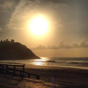 a sunset on a beach with the sun in the sky at Apartamento Pitangueiras - Guaruja in Guarujá