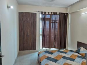 a bedroom with a bed and a large window at Friendly Service Apartment in Ghaziabad