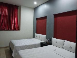 two beds in a hotel room with red curtains at J Alejandro - Centro Histórico Guadalajara in Guadalajara