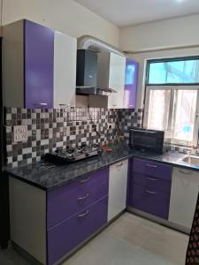 a kitchen with purple cabinets and a sink at Friendly Service Apartment in Ghaziabad +8 photos