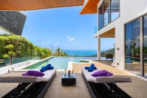 an outdoor patio with purple pillows and a swimming pool at Villa The Wave in Chaweng Noi Beach