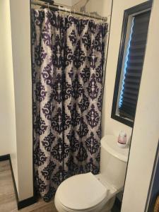 a bathroom with a toilet and a black and white shower curtain at Genesis Get Away in Evergreen