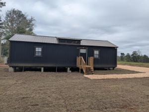 a black tiny house with a staircase in a field at Genesis Get Away in Evergreen