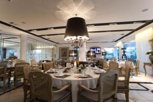 una sala da pranzo con tavoli, sedie e lampadario a braccio di Litohoro Olympus Resort Villas & Spa a Plaka Litochorou
