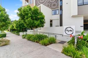 a sidewalk in front of a building with plants at Direct Collective - Rhythm on Beach in Maroochydore