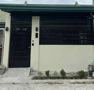 a garage with a black and white door and some plants at Eusel's Place Butuan in Butuan