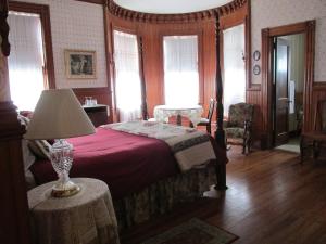 a hotel room with a bed, chair and a mirror at Pensacola Victorian Bed & Breakfast in Pensacola