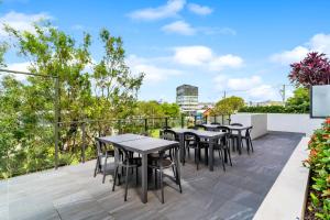 a patio with tables and chairs on a balcony at Direct Collective - Rhythm on Beach in Maroochydore