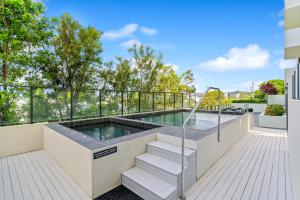 a swimming pool on a balcony with stairs leading to a house at Direct Collective - Rhythm on Beach in Maroochydore