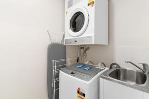 a kitchen with a washing machine and a sink at Direct Collective - Rhythm on Beach in Maroochydore +34 photos