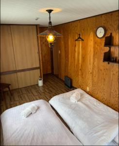 two beds in a room with a clock on the wall at Yama Chalet in Rankoshi