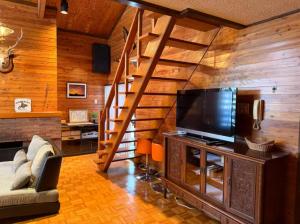 a living room with a staircase and a television at Yama Chalet in Rankoshi