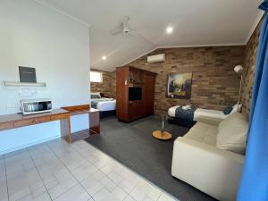 a living room with a white couch and a bedroom at Rest Point Motor Inn in Glen Innes