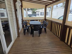 a screened porch with a table and chairs on it at FMLODGE mobil home le petit cocon in Valras-Plage