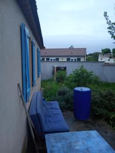 eine Terrasse mit einem blauen Sofa und einem Mülleimer in der Unterkunft Gillet in LʼIsle-sur-la-Sorgue