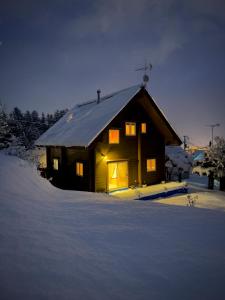 a small house in the snow with lights on at July In Furano in Nakafurano