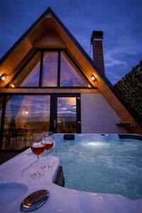 zwei Gläser Wein auf einem Tisch in einem Whirlpool in der Unterkunft A-Frame Prislop,Hațeg in Silvaşu de Sus