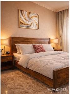 a bedroom with a large bed with two lamps and a painting at NOAZ Hotel Kampala in Kampala