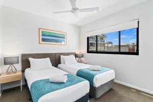 two beds in a room with a window at Direct Collective - Sea Breeze Mooloolaba in Mooloolaba