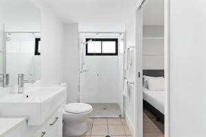 a white bathroom with a toilet and a sink at Direct Collective - Sea Breeze Mooloolaba in Mooloolaba +22 photos