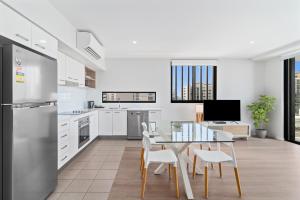 a kitchen and dining room with a table and chairs at Direct Collective - Sea Breeze Mooloolaba in Mooloolaba