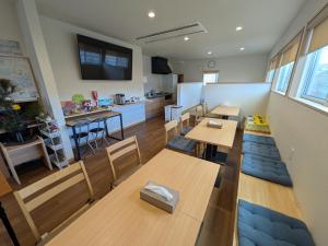a room with tables and chairs and a kitchen at Hiroshima Saijo Youth Hostel in Higashihiroshima