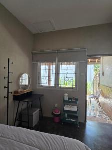 a bedroom with a bed and a desk and windows at Homestay IDR Bali in Jimbaran