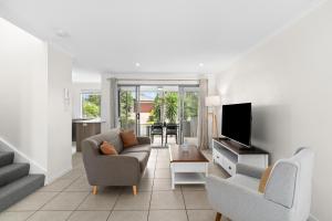 a living room with a couch and chairs and a television at Direct Collective - Breeze on Brightwater in Mooloolaba