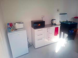 a small kitchen with a microwave and a refrigerator at Rose's Garden Cottages in Lusaka