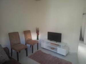 a living room with two chairs and a television at Rose's Garden Cottages in Lusaka