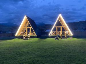 two triangular houses with lights on a field at night at Kolsay Aframe Vibes in Saty +13 photos