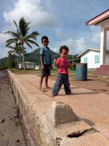 two young boys standing next to a wall at Saumualevu in Kavala