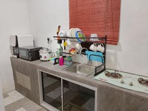 a kitchen counter with a sink and some dishes at Rumah Impian Bapa in Semporna