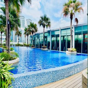 a swimming pool with palm trees in front of a building at Vortex by klcc view in Kuala Lumpur