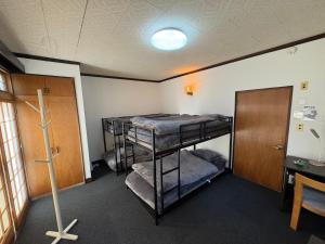 a room with three bunk beds and a desk at ゲストハウス あめりか和 in Namerikawa +9 photos