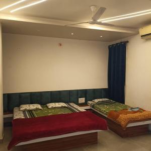 two beds in a room with a ceiling fan at Chavan guest house in Akalkot