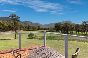 a table and chairs on a deck with mountains in the background at Brokenback Views Country Estate Hunter Valley in Pokolbin