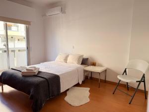 a white bedroom with a bed and a chair at Mimosa flat City Cente 2bdr in Nicosia