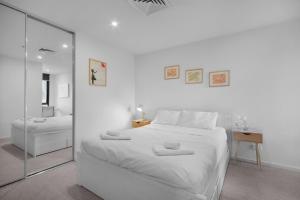 a white bedroom with a large white bed and a mirror at Rooftop infinity pool - St Kilda luxury in Melbourne +24 photos