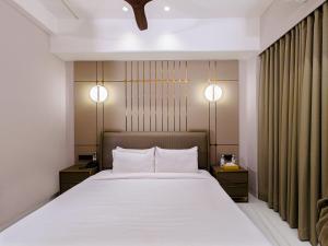 a bedroom with a large white bed with two night stands at SVS Bhawan in Ulhāsnagar