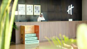 a man is sitting at a counter in a store at Holiday Inn Abu Dhabi by IHG in Abu Dhabi