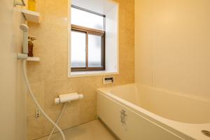 a bathroom with a tub and a window at Dream Bridge Fuji House in Fuji