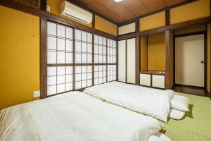 two beds in a room with windows at Dream Bridge Fuji House in Fuji