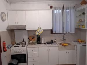 a kitchen with white cabinets and a stove top oven at Studio Lemoni Peloponnese in Pirgákion +1 photo