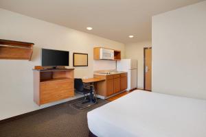 a hotel room with a bed and a desk with a television at WoodSpring Suites Columbus NE I-270 Airport in Gahanna