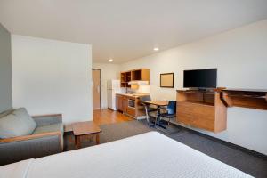 a room with a bed and a desk with a television at WoodSpring Suites Columbus NE I-270 Airport in Gahanna